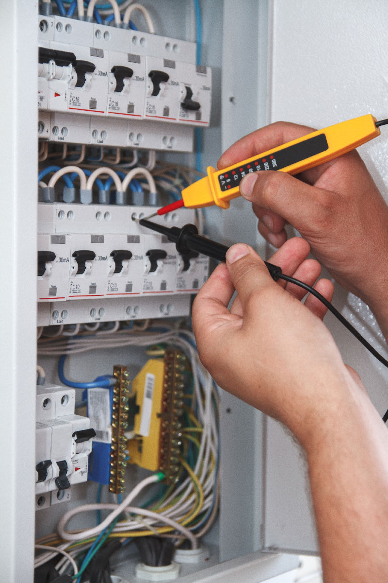 electrician-with-multimeter-probe-at-an-electrical-2023-11-27-04-57-08-utc photo d'une installation électrique