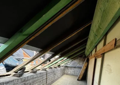Intérieur de la charpente en bois où des chevrons supplémentaires ont été ajoutés pour renforcer la structure.