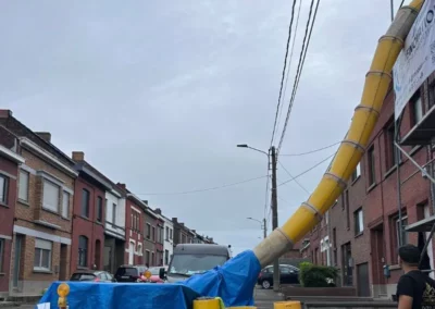 Une goulotte est utilisée pour évacuer les tuiles retirées de la toiture en rénovation. Les tuiles sont dirigées vers un container placé en bas de l'échafaudage.