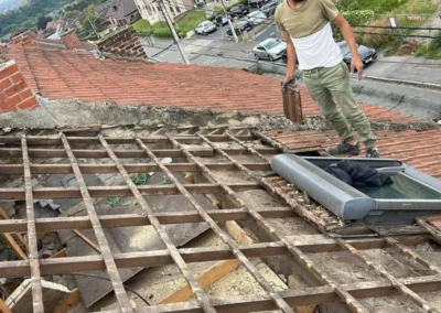 Un couvreu de TS Rénovation est en train inspecté la charpente existante pour évaluer les parties nécessitant une rénovation ou un renforcement.