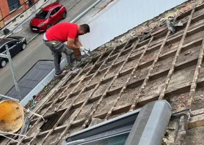 Un couvreur nettoie et prépare la charpente existante avant l'installation de la nouvelle couverture de toiture.
