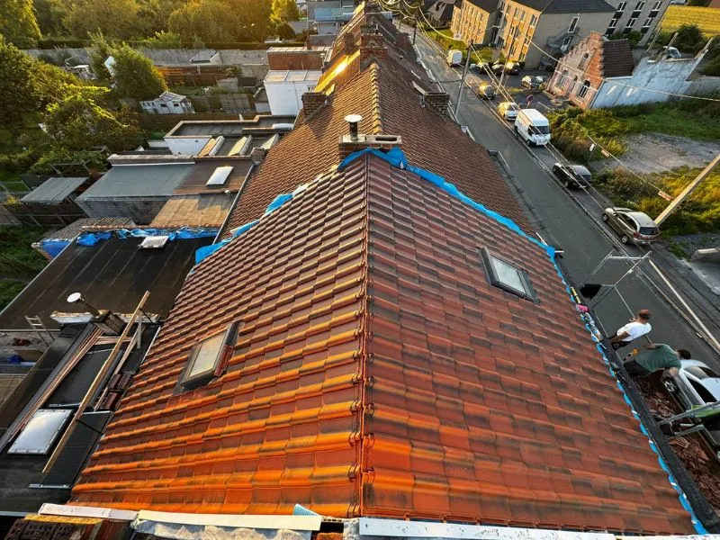 Vue d'ensemble de la nouvelle toiture en tuiles sur une maison. Le toit est recouvert de tuiles rouges, avec deux vélux intégrés pour apporter de la lumière naturelle aux combles. La rénovation assure une parfaite étanchéité et un aspect esthétique harmonieux.