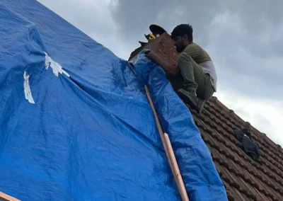 Un couvreur de TS Rénovation est en train de poser une bâche sur le toît pour protéger la maison contre les intempéries lors de la rénovation.