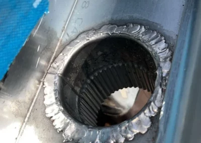 Soudure autour de l'orifice de raccordement pour la descente d'eau pluviale sur une gouttière en métal. Ce travail précis garantit une étanchéité optimale pour éviter les fuites d'eau et assurer la durabilité du système de drainage de la toiture rénovée.