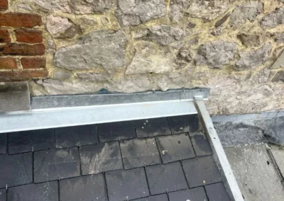 Jonction métallique entre le mur et la toiture en ardoise à l'aide d'un profil en Z.