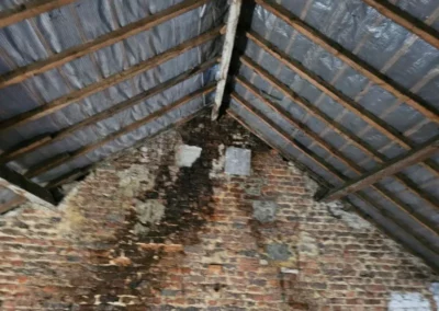 La toiture au-dessus de la panne faîtière n'est plus étanche. Traces d'humidité sur le mur.